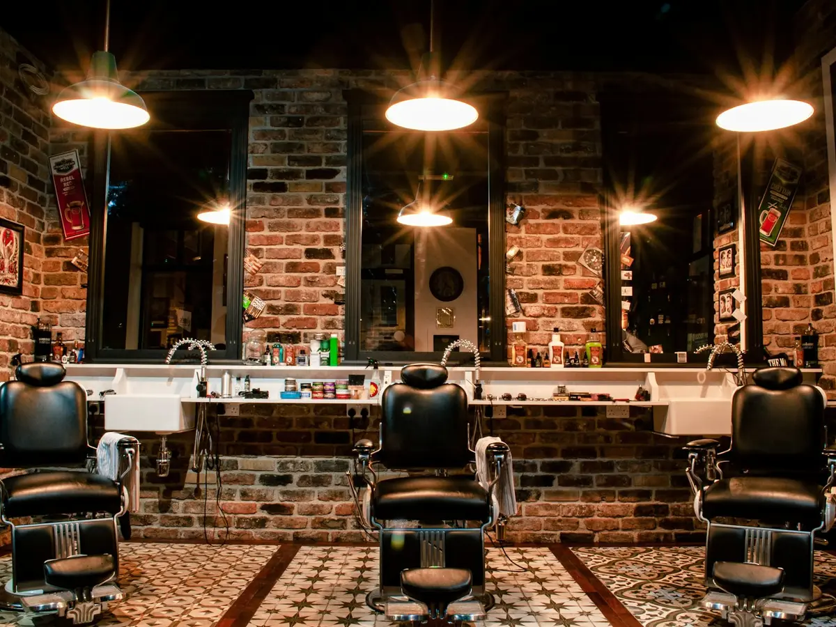 Wnętrze Barbershop Nowak — ceglana ściana, zabytkowe fotele i ciepłe światło